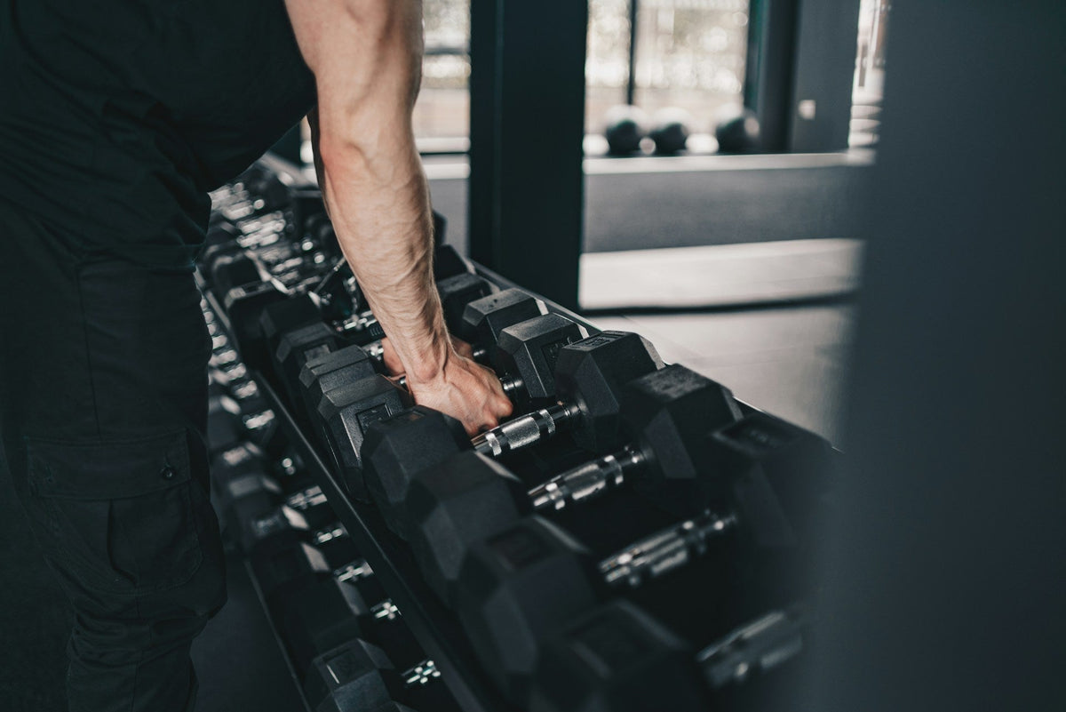 gym trainee gripping a dumbbell about to start his hand strengthening workout
